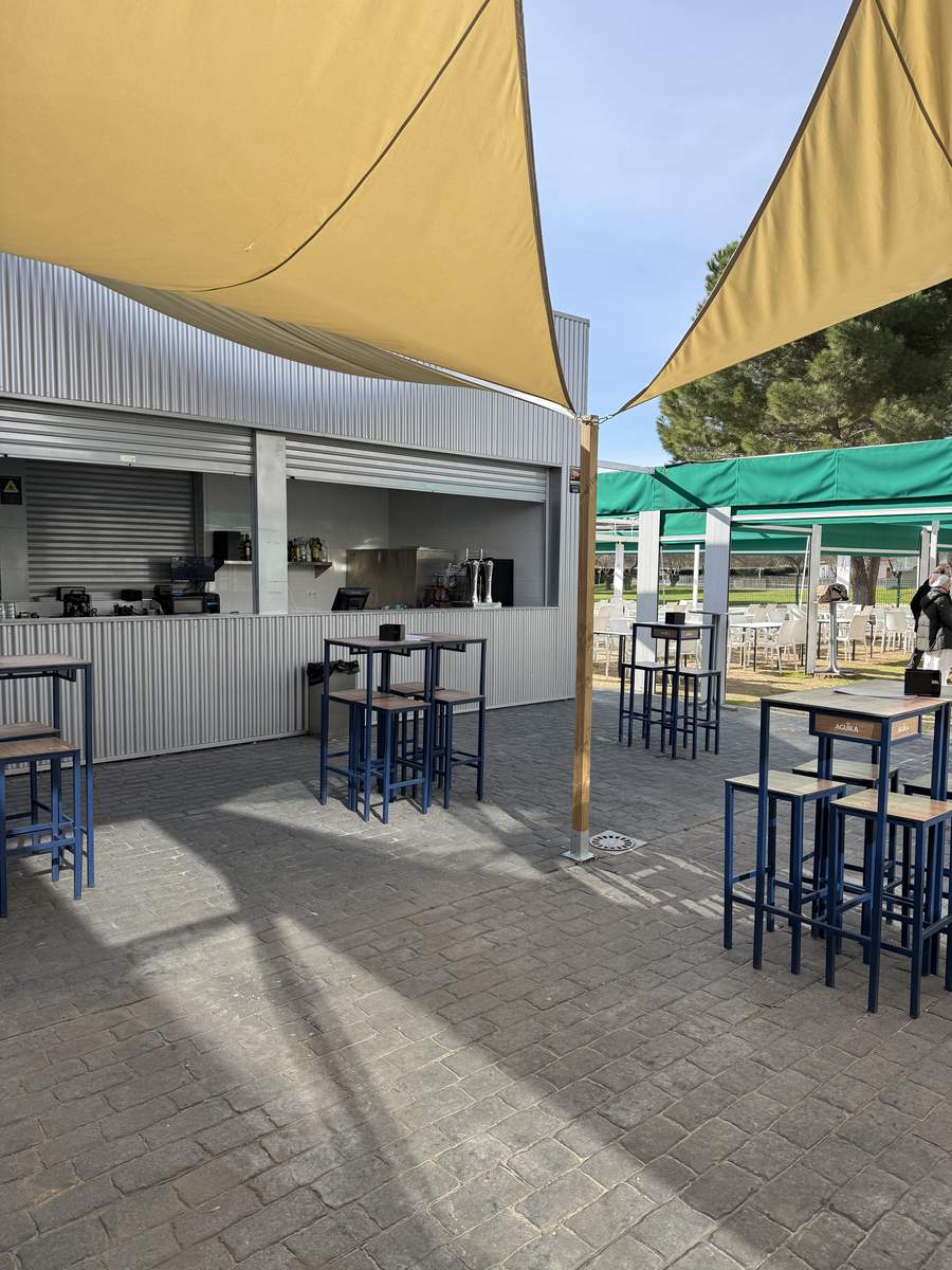 Zona de barra en la terraza exterior con mesas altas y velas de sombra